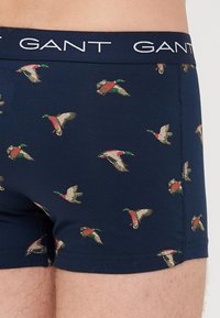 Navy blue boxer briefs with repeated flying mallard duck prints and a dark waistband featuring the "GANT" logo in white.