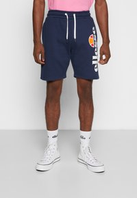 Námořnické bavlněné kraťasy s elastickým páskem a šňůrkou, doplněné bílým logem a designem. V kombinaci s bílými vysokými teniskami a ponožkami.