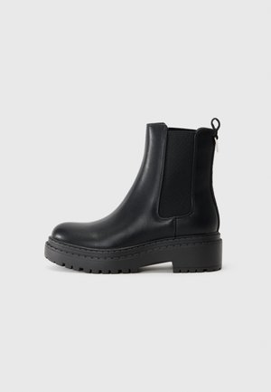Stivale alla caviglia in pelle nera con pannelli elastici laterali, suola in gomma spessa e una sottile linguetta sul retro per una facile vestibilità.