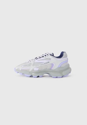 Las zapatillas Lacoste tienen un upper de malla gris con acentos morados, una suela gruesa gris, un collar acolchado y cordones contrastantes.