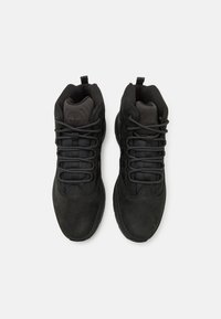 Svarta högskurna vandringsskor med övre del i texturerad mocka, vadderad krage och svarta skosnören. Har en logotyp präglad på tungan.