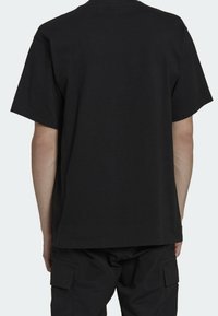 Svart bomullströja med rund hals och korta ärmar. Enkel design utan grafik eller mönster, slät textur, något lös passform.