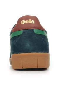 Sneaker in suede blu navy con dettagli verde e un tallone in pelle marrone, caratterizzato da un logo dorato "Gola" e una suola in gomma marrone testurizzata.