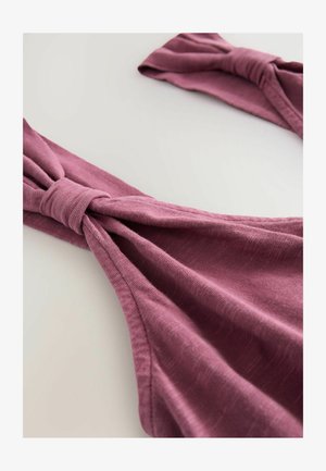 Heledad lilla kangas, millel on pehme tekstuur ja sõlmed detailid rihmadel, loodud mugavuseks ja stiiliks igapäevases kandmises.