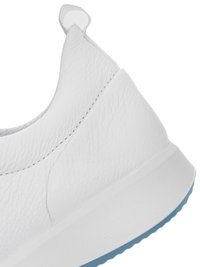 Primer plano del talón de una zapatilla de cuero blanco con parte superior texturizada, pestaña para tirar y suela blanca con una banda de rodadura azul claro.