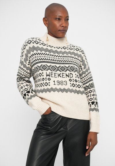 Pulover tricotat de culoare crem, cu modele geometrice negre, având inscripția "WEEKEND 1983". Gât înalt și manșete ribotate pentru un plus de textură.