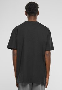 T-shirt en coton noir à manches courtes, col rond et coupe décontractée. Présente une texture lisse sans logos ni motifs visibles.