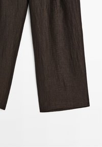 Pantalon large texturé marron foncé, visible de mi-cuisse jusqu'à l'ourlet, sur fond blanc.