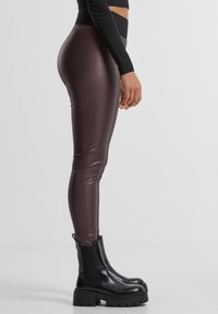 Figursyede leggings med høj talje i mørkebrunt, skinnende materiale. Kombineret med chunky sorte ankelstøvler med tekstureret sål.