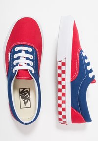 Rode en blauwe canvas sneakers met witte veters, een witte zool en een ruitpatroon aan de zijkant. Klassiek laag ontwerp, vlakke textuur.