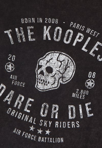 Juodas marškinėliai, pagaminti iš audinio, su baltais nusidėvėjusiais užrašais ir kaukolės grafika. Užrašai apima "The Kooples," "Dare or Die" ir karinę simboliką.