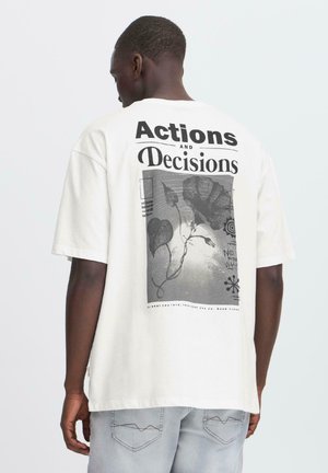 White cotton t-shirt featuring a bold black graphic on the back with the text "Actions and Decisions" and floral patterns. Short sleeves, relaxed fit.