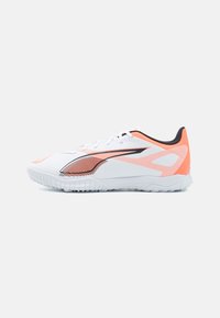 Hvid sportsko med orange og sorte detaljer, der har et strømlinet design, tekstureret overdel og en fleksibel gummisål for godt greb.