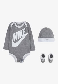Grå bomullsbodysuit för baby med långa ärmar, vit kant, stor vit "NIKE"-logga, matchande grå hatt och tossor med logga.