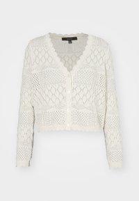 Vit kort cardigan i stickad tyg med diamantmönster, utrustad med V-ringning, knappstängning och vågig nederkant.