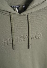 Sudadera color verde oliva con un tejido texturizado. Presenta un logo de la marca "MORATO" bordado, cordones y una capucha forrada.