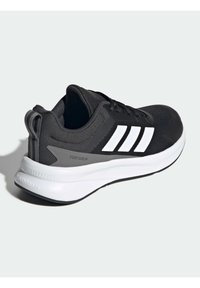 Baskets de sport noires avec un dessus en mesh texturé, design à trois bandes blanches et une épaisse semelle en mousse blanche étiquetée "CLOUDFOAM."