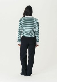Striped long-sleeve shirt in green and white with a white collar, paired with black wide-leg trousers. Focus on the back view.