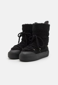 Zwarte hoge sneakers met een fluffy textiele bovenkant, een gestructureerde vetersluiting en een stevige zwarte rubberen zool. Accenten zijn onder andere hardware in goudtint.