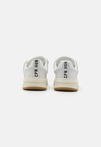 Weiße Ledersneaker mit beigefarbenen Sohlen, die ein Rückenpaneel mit der Aufschrift „CPN HGN“ in Schwarz aufweisen. Mit runder Zehenform und gepolstertem Kragen.
