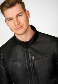 Black leather jacket with a high collar, front zipper, and a side zip pocket. The material has a smooth, slightly textured finish.