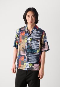 Short-sleeve button-up shirt featuring a multicolored abstract print with various illustrations, text, and patterns on a dark background.