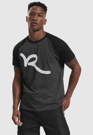 Manches raglan noires sur un t-shirt en coton gris foncé avec un grand logo blanc. Le design présente un col rond et une coupe décontractée.