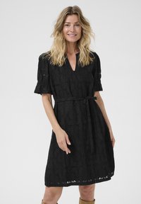 Rochie neagră din dantelă cu mâneci bufante scurte, decolteu în V, cordon la talie și model floral. Fusta are detalii decupate la tiv.