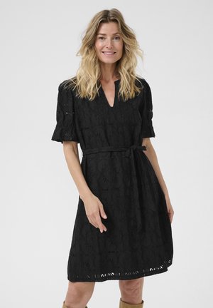 Black lace dress with short puff sleeves, a V-neck, waist tie, and floral pattern. The skirt has cut-out details at the hem.