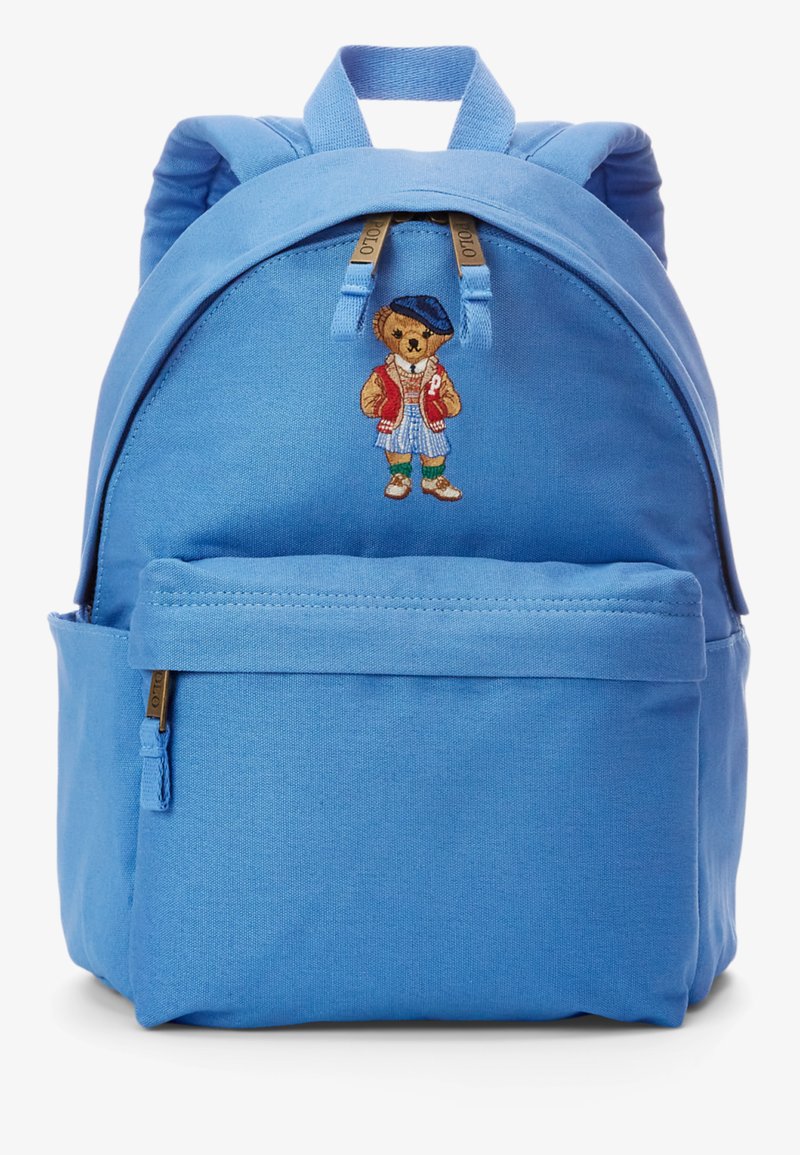 Μπλε σακίδιο από ύφασμα, με εμπρόσθια τσέπη και κεντητό σχέδιο αρκούδας στη ζώνη, με ρυθμιζόμενους ιμάντες και χερούλι στην κορυφή.