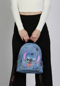 Mochila azul de piel sintética con diseño de Stitch en caricatura. Cierre de cremallera, correas acolchadas y bolsillos laterales para mayor funcionalidad.