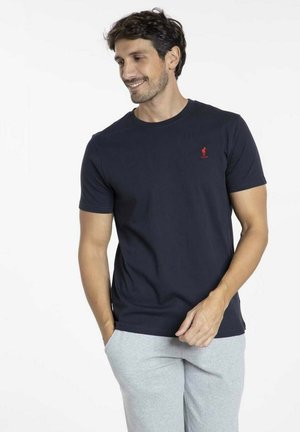 T-shirt en coton bleu marine avec un col rond, des manches courtes et un petit logo rouge sur la poitrine. Coupe décontractée et texture lisse.