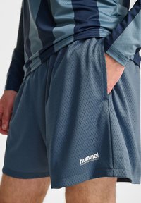 Nät, marinblå sportshorts med sidofickor. Funktioner inkluderar logotyp på nedre fållen. Lätt, andningsbart tyg med perforerad textur.