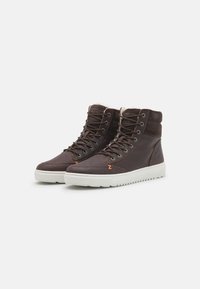 Bruine leren high-top sneakers met witte rubberen zolen, voorzien van een vetersluiting, gewatteerde kraag en contrasterende oranje stiksels.