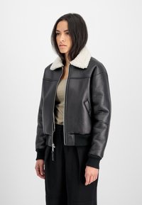 Veste bomber en cuir noir avec un col en shearling, fermeture éclair à l'avant, poignets et ourlet côtelés ; matière texturée et coupe courte.