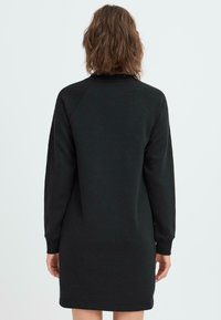 Musta college-mekko pitkähihaisilla, ribbaus- hihoilla ja pyöreällä kaula-aukolla. Valmistettu pehmeästä kankaasta, suorassa leikkauksessa ja minimaalisen ompelusyynteille.