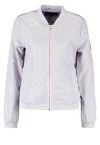 Veste bomber gris clair en nylon avec fermeture éclair frontale, poignets côtelés et poche latérale. Caractérisée par une texture lisse et un design minimaliste.