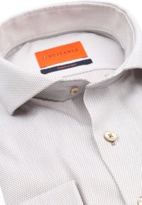 Lichtgepatroneerd non-iron shirt met een kraag, gemaakt van stof in tinten wit en beige. Heeft beige knopen en een label.
