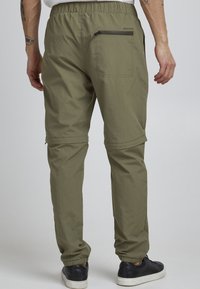Lightweight, olive-green cargo pants with an elastic waist, zipper pocket on the back, and adjustable cuffs. Smooth texture, streamlined design.
