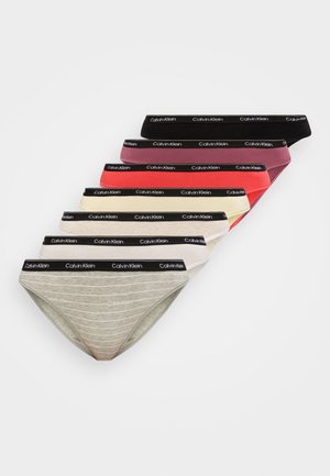 Šest ženski Calvin Klein bikini hlačk v črni, bordo, rdeči, kremni, beli in sivi barvi, z elastičnim pasom z logotipom, razporejenih v obliki ventilatorja.