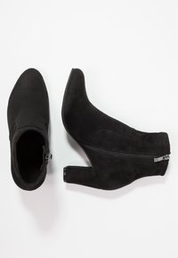 Bottines noires en daim, dotées d'une fermeture éclair latérale, d'un bout effilé et d'un talon moyen à finition mate.