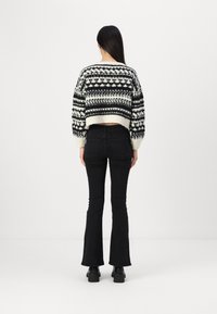 Melnbalts rakstains nožogots džemperis ar apaļu kakla izgriezumu, apvienots ar melniem platām ikrām un potīšu zābakiem. Gluda trikotāžas auduma tekstūra.