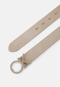 Beige nepleren riem met een textuur van diamanten patronen, taps toelopende uiteinden en een ronde metalen gesp met een minimalistisch ontwerp.