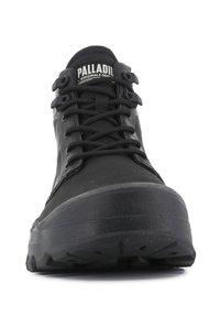 Botín negro de corte medio con parte superior texturizada, cierre de cordones, suela de goma y punta reforzada. Logo de PALLADIUM visible en la lengüeta.