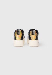 Black platform sneakers with synthetic upper, featuring an iridescent accent and white textured rubber sole. Logo on the back.