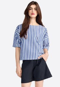 Haut à manches courtes bleu et blanc à rayures, avec un col bateau, associé à un short noir. Il présente une coupe décontractée et une texture de tissu douce.