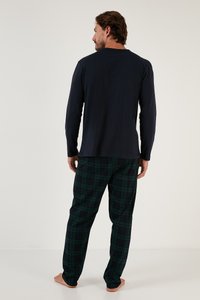 Camisetă cu mânecă lungă de culoare bleumarin, asortată cu pantaloni în carouri verzi. Cămășa este netedă, în timp ce pantalonii au o textură moale și un model în carouri.