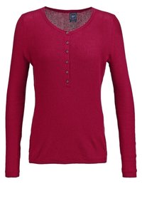 Rode langmouwen henley top met een gestructureerde stof, voorzien van een ronde halslijn en een knoopsluiting aan de voorkant.