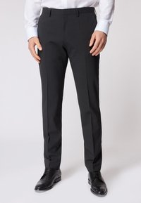 Pantaloni grigio scuro su misura con una texture liscia, dotati di una parte frontale piatta, gambe dritte e tasche laterali, abbinati a scarpe nere.