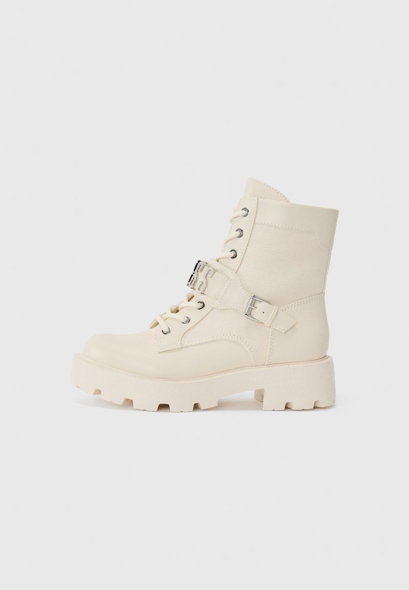 Bottines en cuir crème avec un mélange de cuir lisse et de toile texturée. Semelle en caoutchouc épaisse avec un avant lacé et des détails de sangle ajustable.
